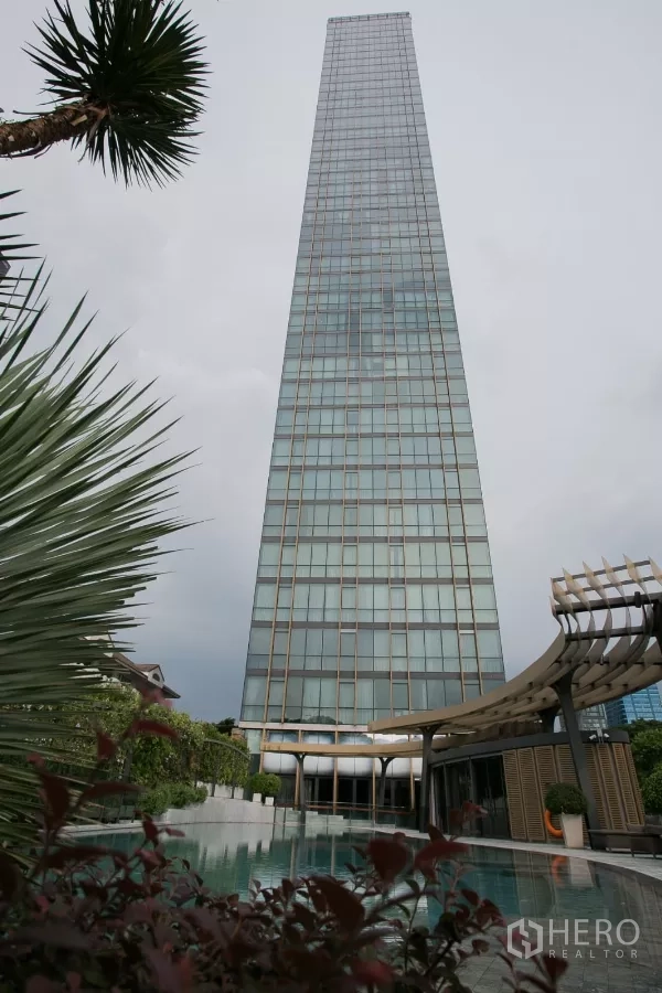 公寓 出租在Watthana, Bangkok - 玻璃幕墙高楼耸立于泳池与花园之上。