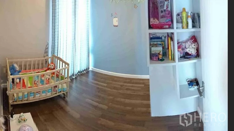Condominium for rent or sale in Watthana, Bangkok - Child’s room with crib, built-in wall shelves, wood flooring and full-height curtains.