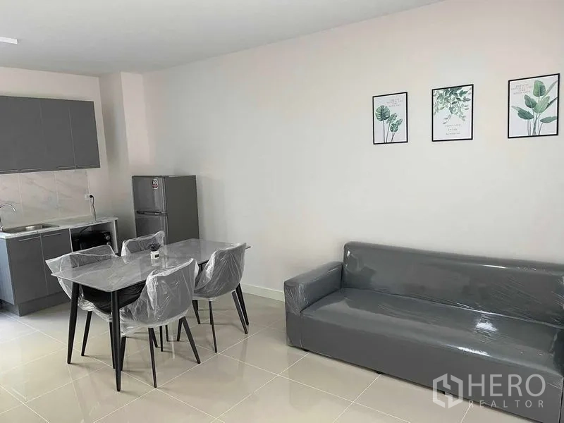 联排别墅 出租在Prawet, Bangkok - 客餐厅另一角度，展示沙发、餐桌与小厨房。