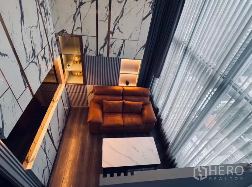 Condominium for rent in Chatuchak, Bangkok - Top-down view of the duplex lounge highlighting high ceilings and marble-paneled walls.