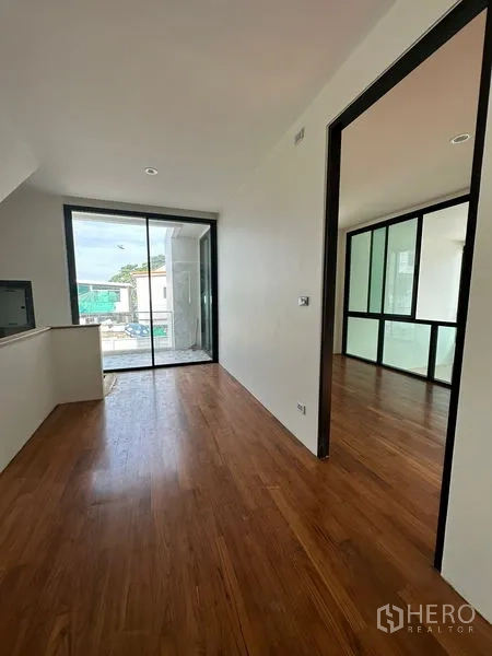 独立式住宅 出租在Watthana, Bangkok - 走廊设有推拉玻璃门通阳台，旁边房间为玻璃隔断墙。