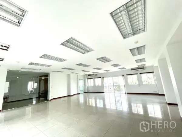 办公空间 出租在Bang Rak, Bangkok - 开放工位区，设玻璃隔断会议室，多扇窗户与荧光吊顶灯。