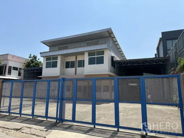 货栈 出租在Bueng Kum, Bangkok - 仓库连两层办公楼外观，蓝色钢制大门与宽阔水泥前院。