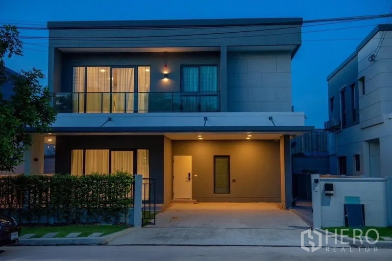 Detached House for rent in Bang Phli, Samut Prakan - Two-storey modern house exterior at dusk with balcony and carport lighting.