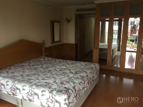 คอนโด ให้เช่าในKhlong Toei, Bangkok - ห้องนอนหลักพื้นไม้พร้อมตู้เสื้อผ้าบานกระจกและทางออกสู่ระเบียง