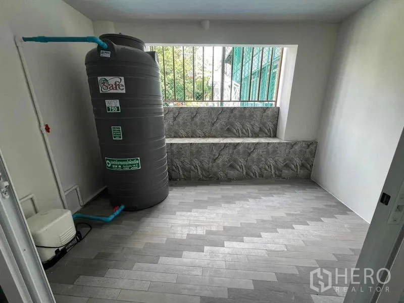 Townhouse for rent in Khlong Toei, Bangkok - Utility area with 750‑liter water tank, pump and gray floor tiles.