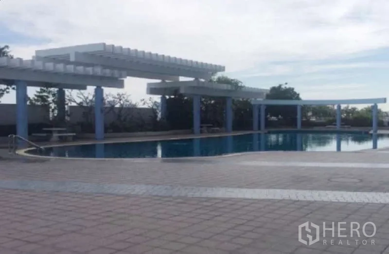 Condominium for sale in Huai Khwang, Bangkok - Outdoor swimming pool with pergola shade structures and paved deck.