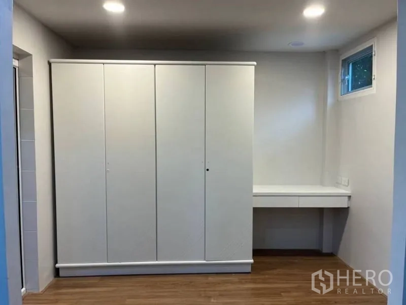 独立式住宅 出租在Samut Prakan - 内置白色衣柜与梳妆台，上方有小窗。