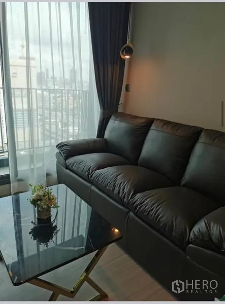 Condominium for rent in Huai Khwang, Bangkok - Leather sofa beside full-height windows offering skyline views