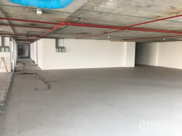 零售空间 出租在Khlong Toei, Bangkok - 开放式零售铺面，灰色地砖、白色墙面，裸露混凝土天花配红色消防管与蓝色风管。