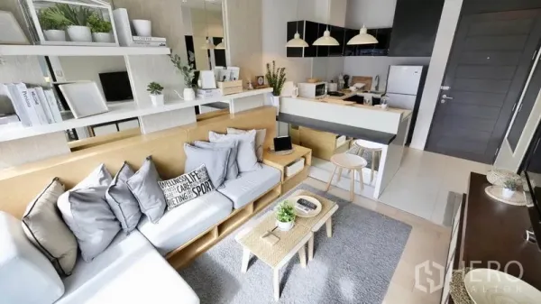 Condominium for rent or sale in Khlong Toei, Bangkok - Wide view of the living area with mirror wall, cushioned sofa and dining peninsula beside the kitchen.