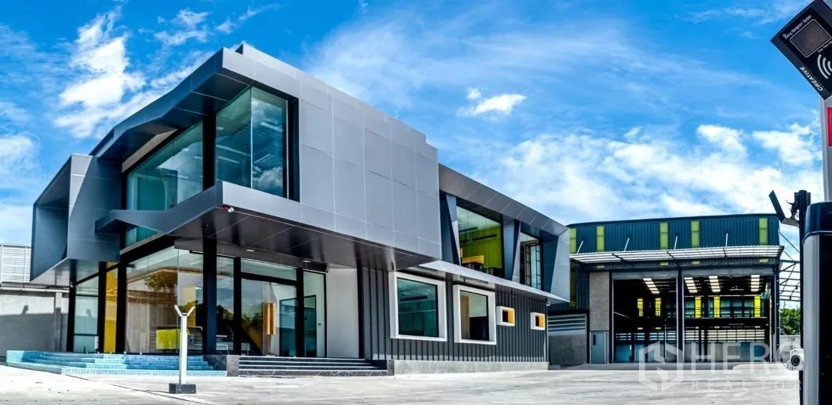 Warehouse for sale in Bang Khen, Bangkok - Panoramic view of glass‑front office and warehouse with security barrier.
