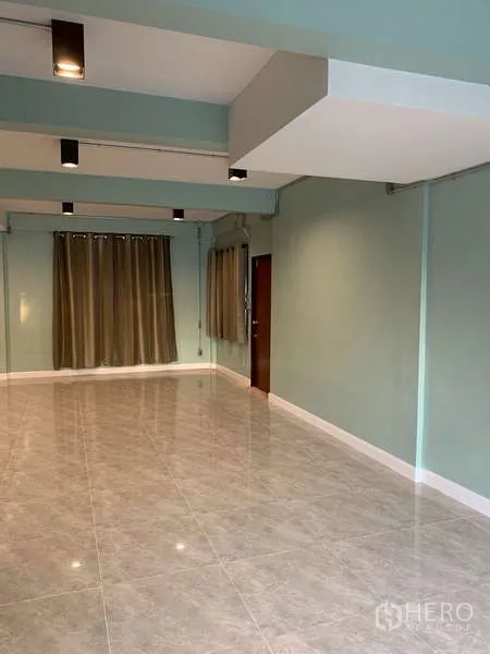 独立式住宅 出租或出售在Phra Khanong, Bangkok - 宽大的客厅，瓷砖地面、外露梁与长窗帘。