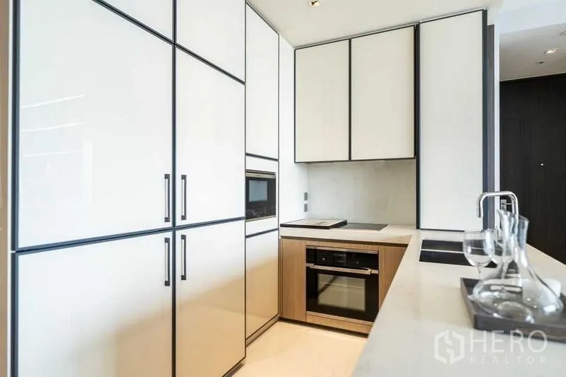 คอนโด ให้เช่าในKhlong Toei, Bangkok - ครัวรูปตัว U ตู้บิวท์อินสีขาว เตาอินดักชัน และเตาอบพร้อมไมโครเวฟ