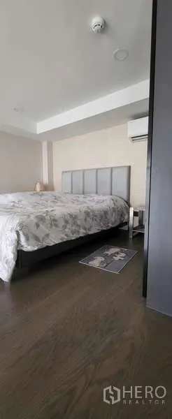 Condominium for rent - Cozy bedroom with upholstered headboard and wooden flooring.