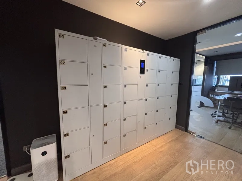 办公室 for rent in Bang Rak, Bangkok - 一排白色员工储物柜，旁为会议室与走廊。