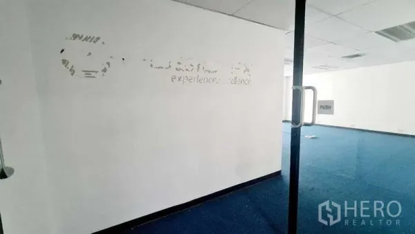 สำนักงาน ให้เช่าในKhlong Toei, Bangkok - มุมมองผ่านประตูกระจกเข้าสู่พื้นที่สำนักงานแบบโอเพ่นแปลน พรมสีน้ำเงิน เพดานหลุม