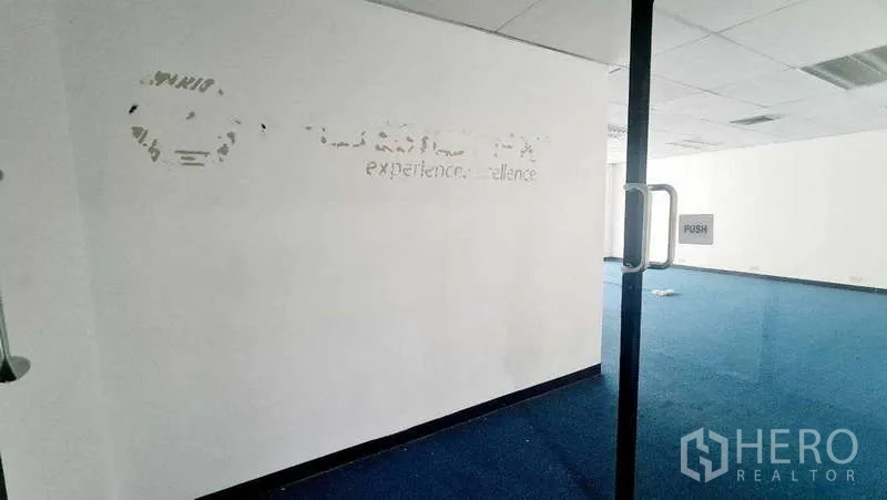 สำนักงาน ให้เช่าในKhlong Toei, Bangkok - มุมมองผ่านประตูกระจกเข้าสู่พื้นที่สำนักงานแบบโอเพ่นแปลน พรมสีน้ำเงิน เพดานหลุม