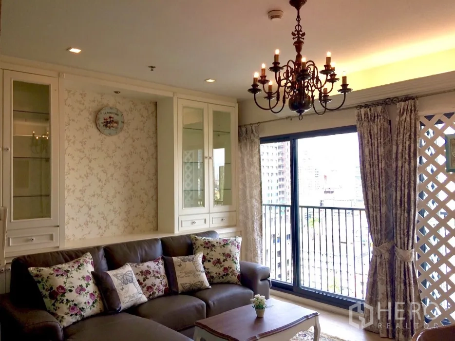 คอนโด ให้เช่าในKhlong Toei, Bangkok - มุมนั่งเล่นสว่างเชื่อมสู่ระเบียงวิวเมือง ประตูกระจกบานเลื่อน โคมระย้า และตู้บิลท์อินสไตล์คลาสสิก