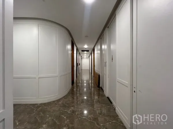 零售空间 出租在Watthana, Bangkok - 长走廊，白色房门成列，大理石地面通往私人房间