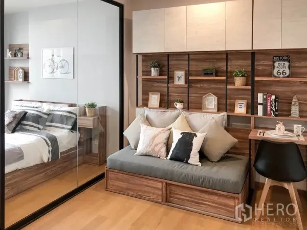 公寓 出租在Bang Rak, Bangkok - 温馨客厅，木质置物墙与沙发榻，玻璃隔断连接卧室。