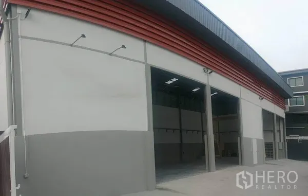 Warehouse for rent in Saphan Sung, Bangkok - Modern warehouse facade with large roller doors and red cladding panels.