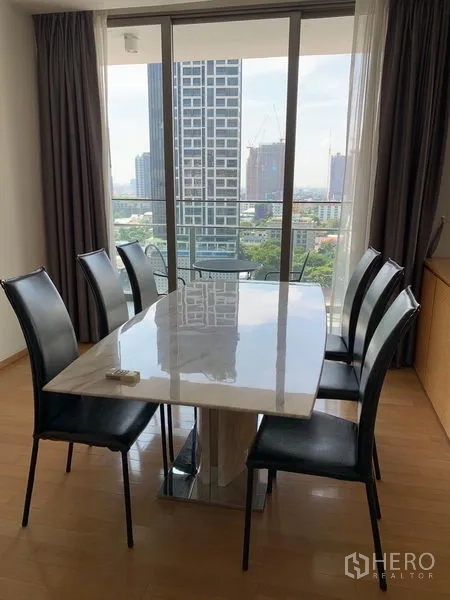 Condominium for rent in Watthana, Bangkok - Dining area for six with balcony access and panoramic city skyline.
