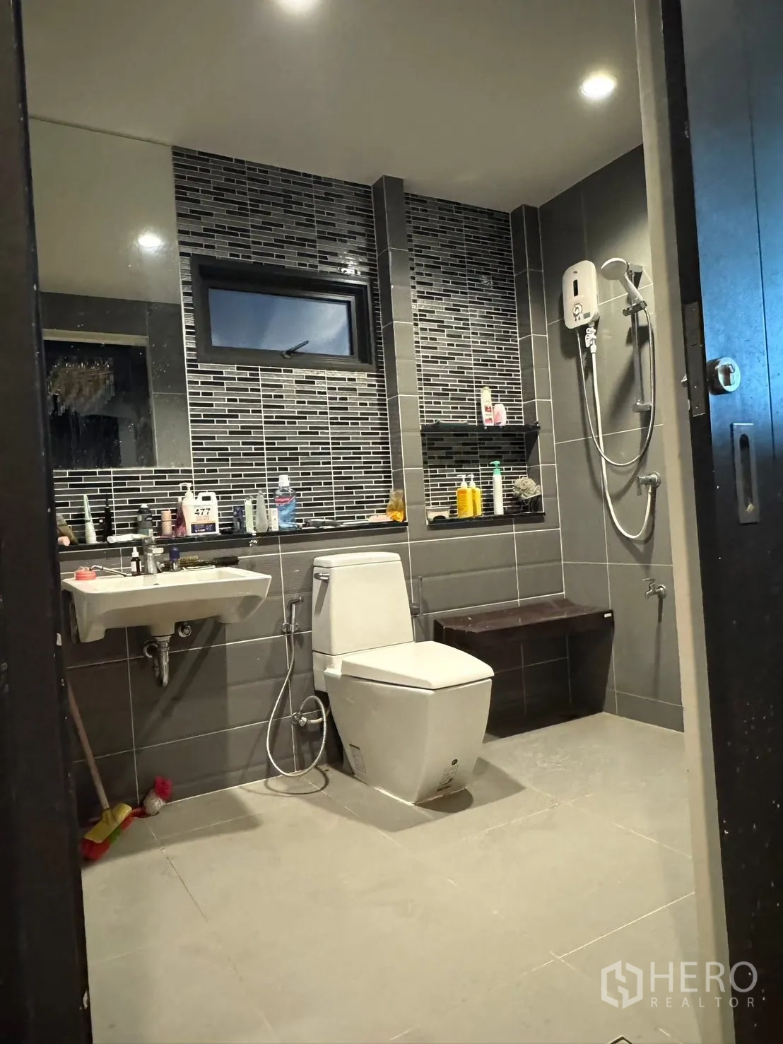 独立式住宅 出售在Mueang Pathum Thani, Pathum Thani - 深色瓷砖卫浴，花洒与小坐凳。