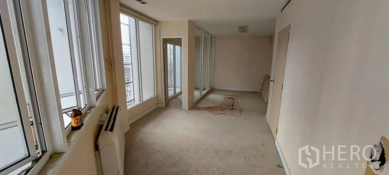 Shophouse for sale - Long hallway lined with windows and sliding glass doors.