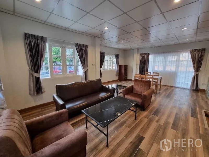 独立式住宅 出租在Mueang Nonthaburi, Nonthaburi - 开放式客餐厅，沙发组、大窗户与木纹地砖。