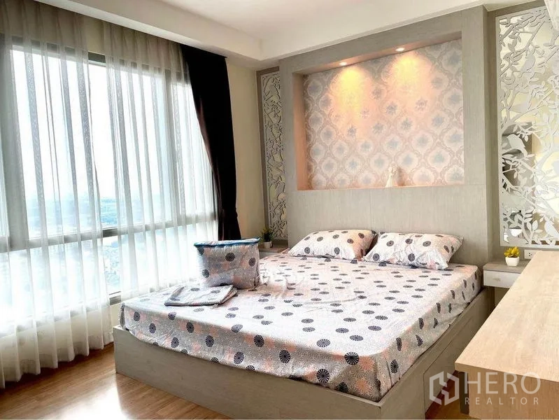 Condominium for rent in Huai Khwang, Bangkok - Primary bedroom with accent-lit headboard, large windows and city view.