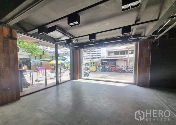 零售空间 出租在Bang Rak, Bangkok - 开放式室内，超宽玻璃门面向街景，水泥地与裸顶灯具。
