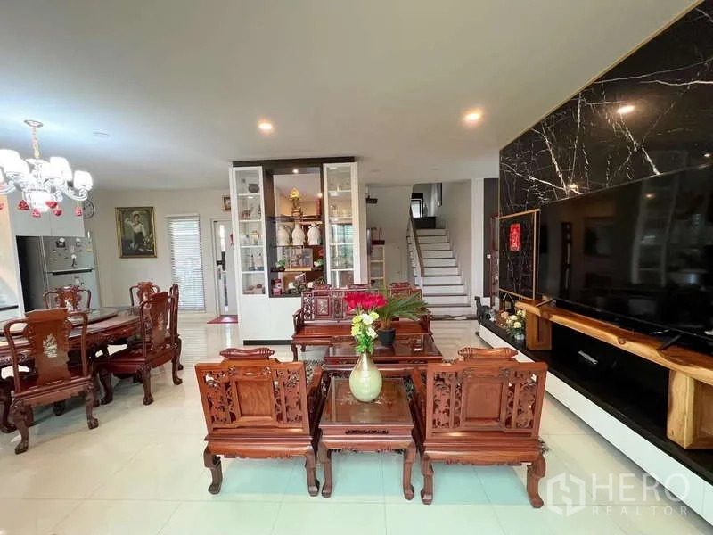 Detached House for sale in Prawet, Bangkok - Lounge facing a black marble feature wall with a large TV and staircase beyond.