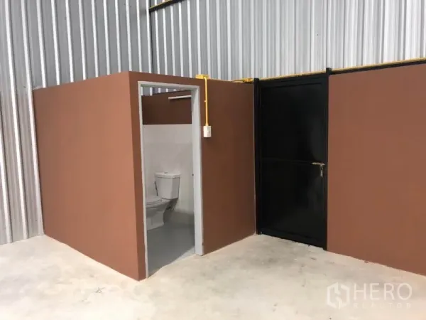 คลังสินค้า ให้เช่าในKhlong Luang, Pathum Thani - ห้องน้ำภายในโกดังและประตูบริการสีดำ