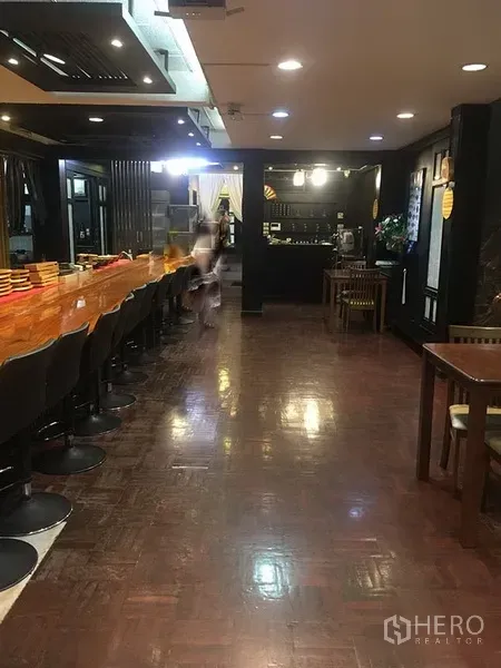 零售空间 出租在Khlong Toei, Bangkok - 室内长木质吧台配高脚椅与筒灯，亮面木地板。