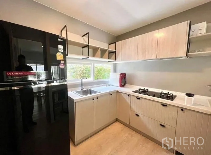 บ้าน ให้เช่า - ครัวสมัยใหม่รูปตัว U มีเตาแก๊ส ตู้บิวท์อินลายไม้โทนอ่อน และตู้เย็นขนาดใหญ่