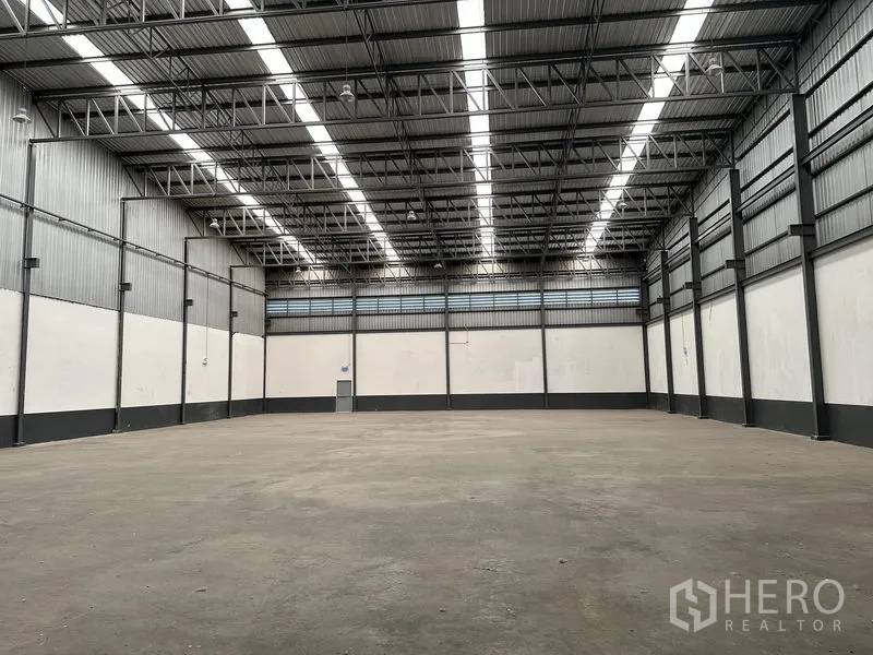 Warehouse for rent in Samut Prakan - High-clear warehouse hall with steel truss roof, skylights, and concrete floor.
