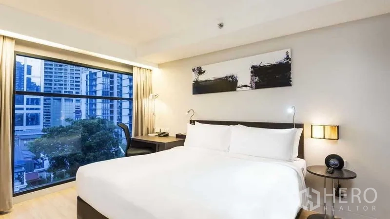Apartment for rent in Watthana, Bangkok - Bedroom with large window, city skyline view and queen bed.