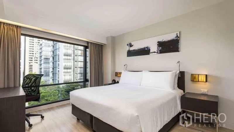Apartment for rent in Watthana, Bangkok - Bedroom with king bed, work desk and wide window overlooking Bangkok skyline.