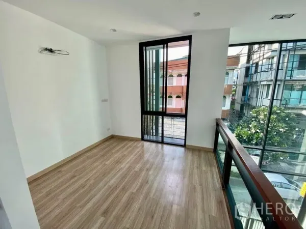 Home Office for sale in Wang Thonglang, Bangkok - Sunlit upper-level room with glass railing and tall sliding windows overlooking the street.