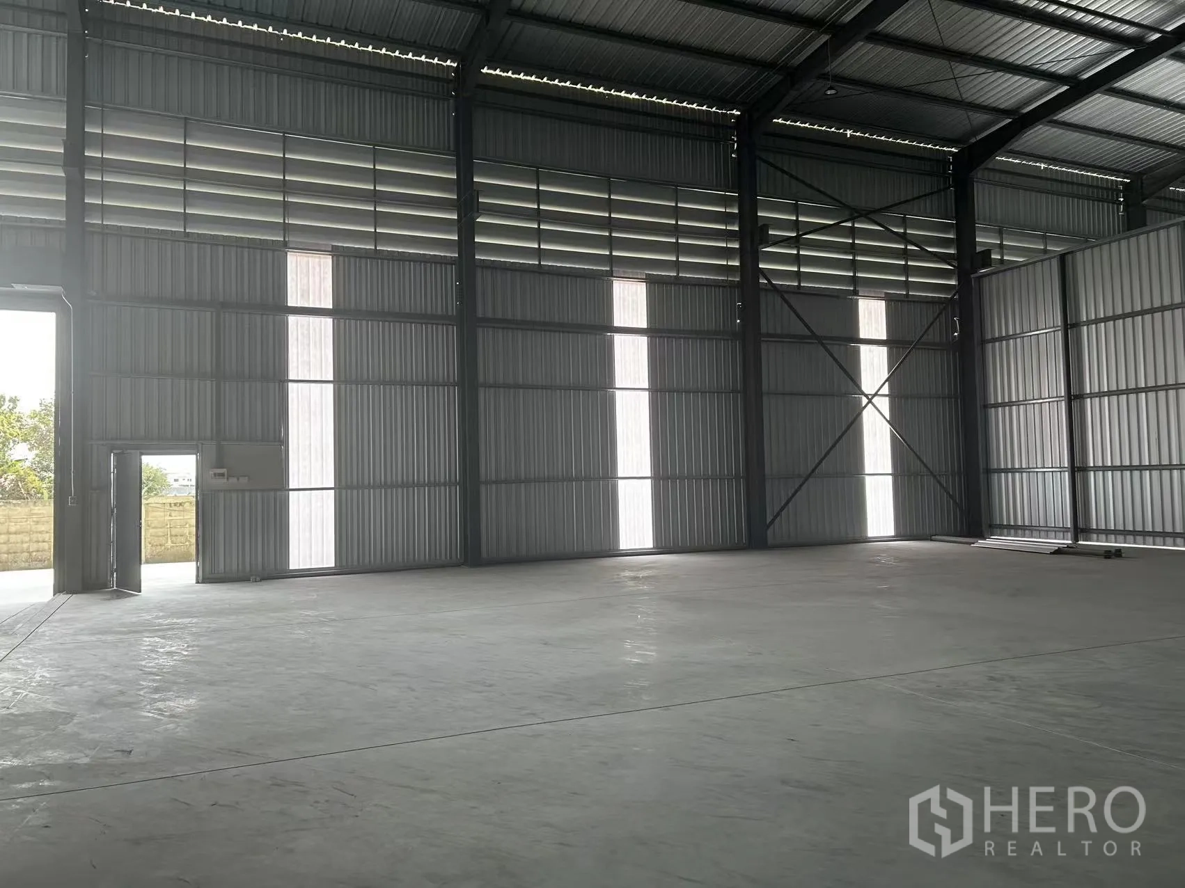 Warehouse for rent in Lam Luk Ka, Pathum Thani - Warehouse interior with steel frame, high roof, concrete floor, and ventilation louvers.