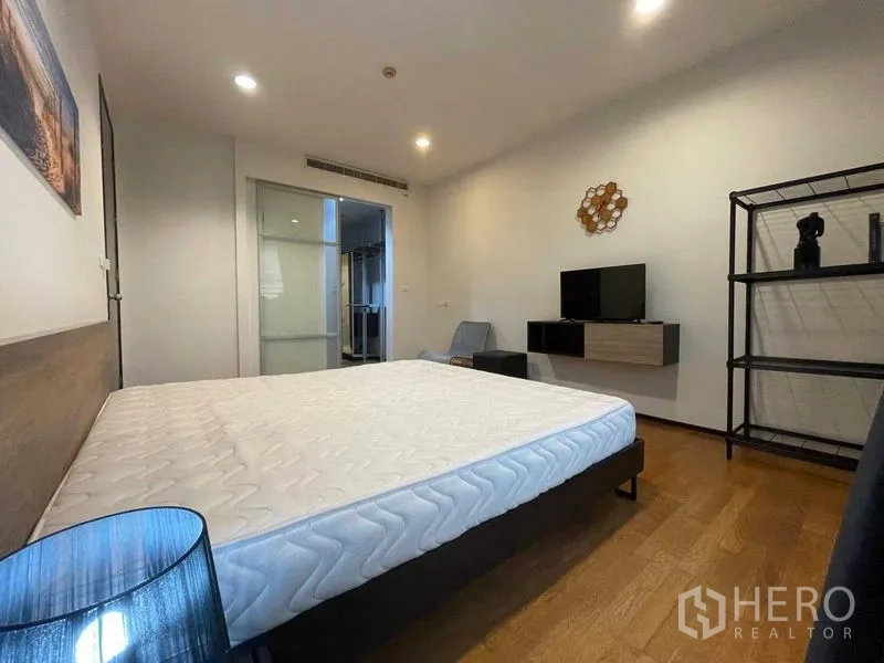 Condominium for rent in Din Daeng, Bangkok - Spacious master bedroom with queen bed, wood flooring, TV console and open shelving in a Din Daeng condo.