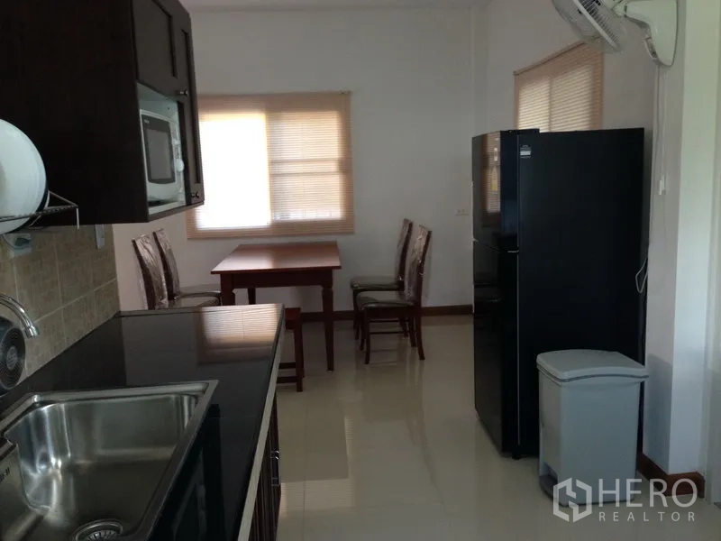 独立式住宅 出售在Phra Khanong, Bangkok - 配套厨房，黑色台面、不锈钢水槽、吊柜、冰箱与用餐角。