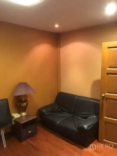 店屋 出租在Bang Rak, Bangkok - 温馨色调的休息角，黑色皮沙发与边几。