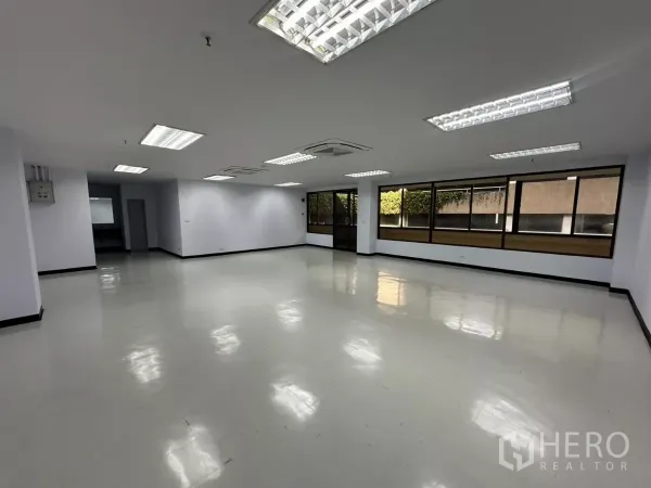 Office Space for rent - Spacious unfurnished office showing glass entry door, long window wall and glossy floors.