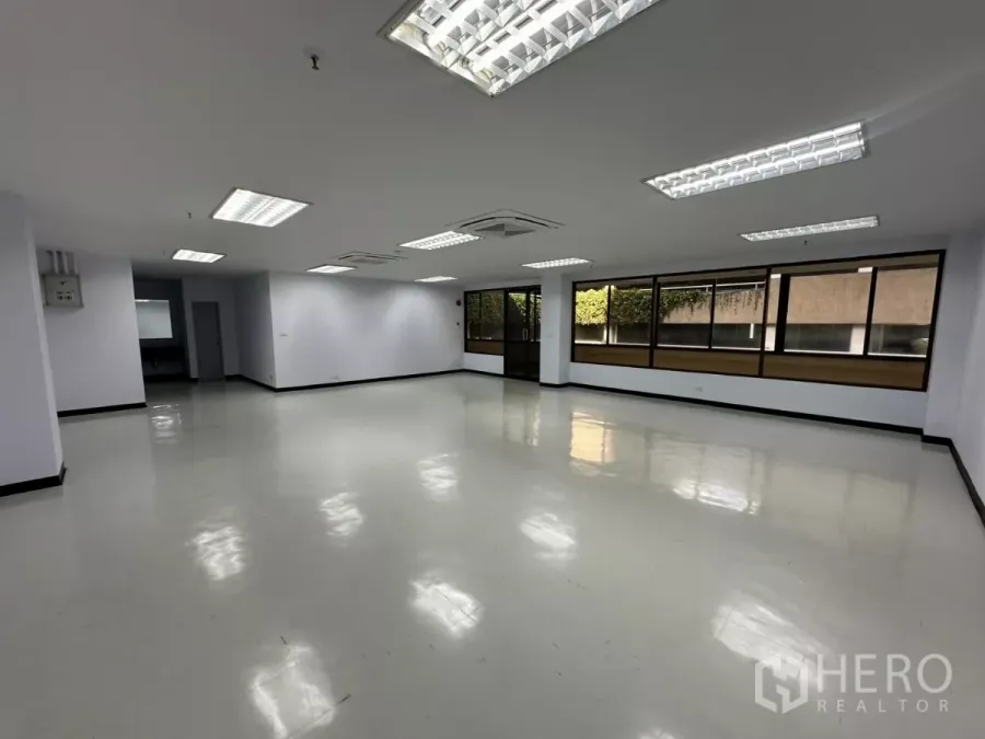 Office Space for rent - Spacious unfurnished office showing glass entry door, long window wall and glossy floors.