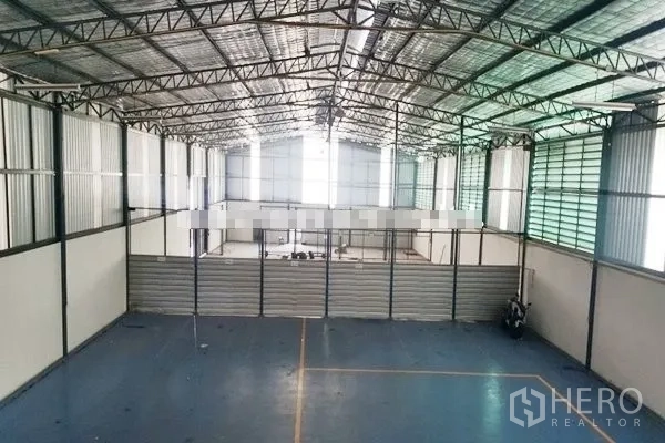 Warehouse for rent in Suan Luang, Bangkok - Spacious high-ceiling warehouse hall with steel truss roof and ventilated side panels.