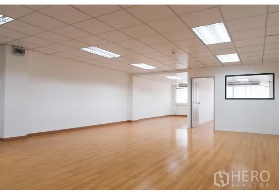Office Space for rent in Bang Rak, Bangkok - Spacious office room with wood flooring, white walls, and fluorescent lighting in a suspended ceiling.