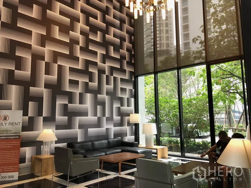 公寓 出租在Khlong Toei, Bangkok - 挑高大堂，几何纹理特色墙、吊灯与舒适等候区。
