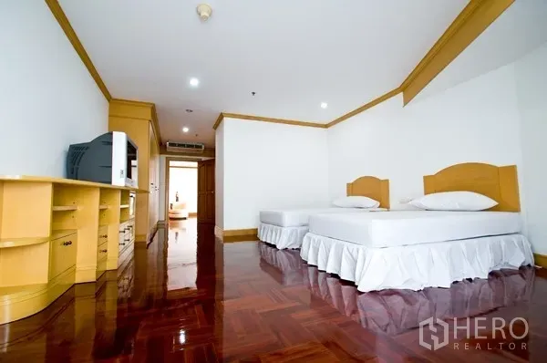 房间 出租在Khlong Toei, Bangkok - 明亮的次卧，配两张单人床、内置储物与亮泽木地板。